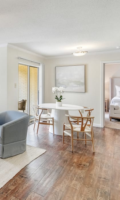 A living room with a grey sofa, a white armchair, a wooden coffee table, and a white bed in the background. at Cambridge Station Apartment Homes, Oxford, 38655