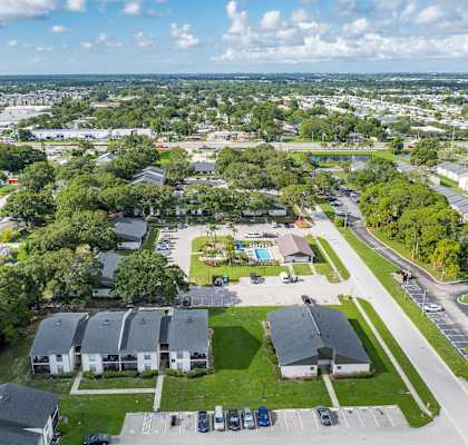 A bird's eye view of a residential area with houses, trees, and a parking lot.