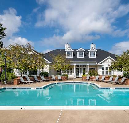 a swimming pool with chairs around it in front of a house