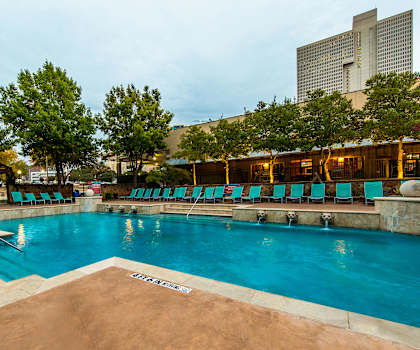 The turquoise outdoor pool with pool chairs, tables, and chairs at Firestone at West 7th. 