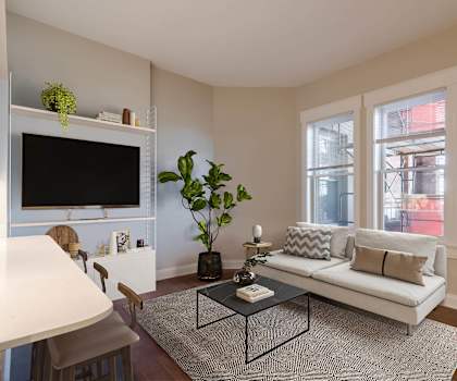 A living room with a white couch, a coffee table, and a flat screen TV.