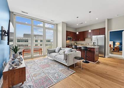 A modern kitchen with a dining table and chairs is visible through a glass door.
