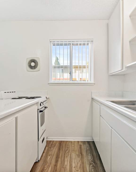A white kitchen with a window and a stove top oven. at Canyon Shadows Apartments, Riverside, CA