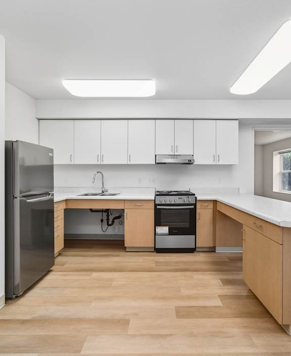 A kitchen with a refrigerator, oven, and sink.