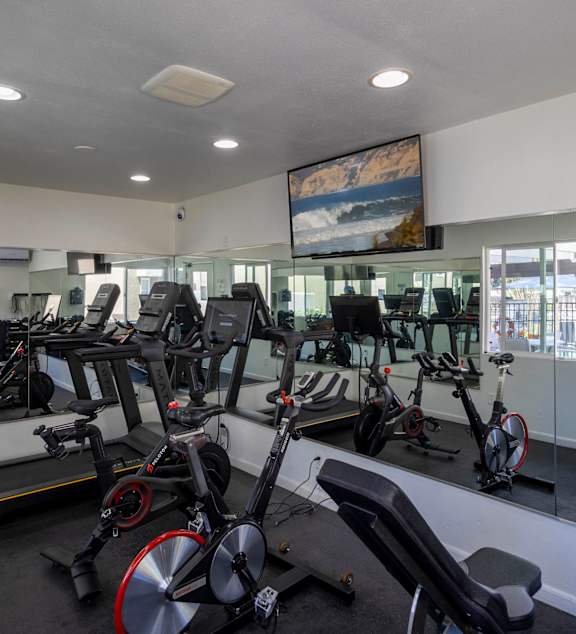 Fitness center with cardio machines and mirrored walls at Bella Del Mar Apartments, Del Mar, California
