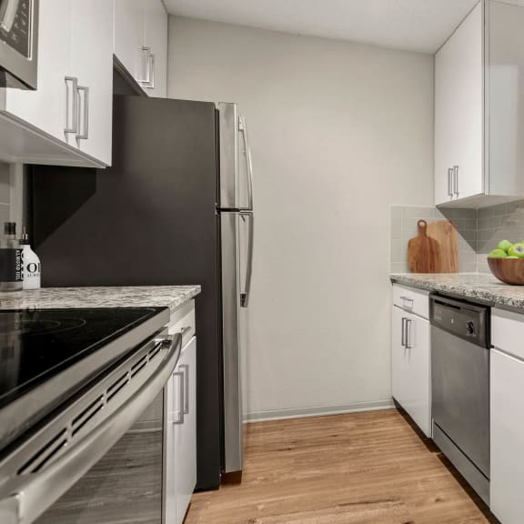 a kitchen with white cabinets and stainless steel appliances at South Lamar Village, Austin, TX