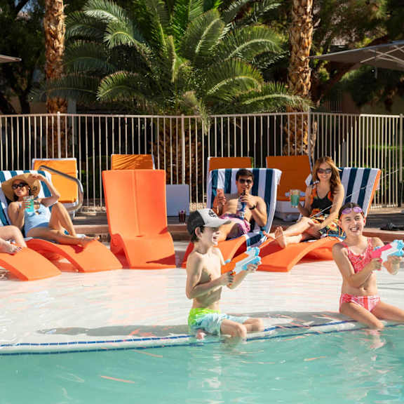 People are relaxing by the poolside on sun loungers.