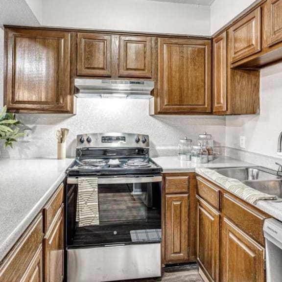 a kitchen with wooden cabinets and a stove and a sink at Diamond Ridge Apartments, Oklahoma City, OK, 73114