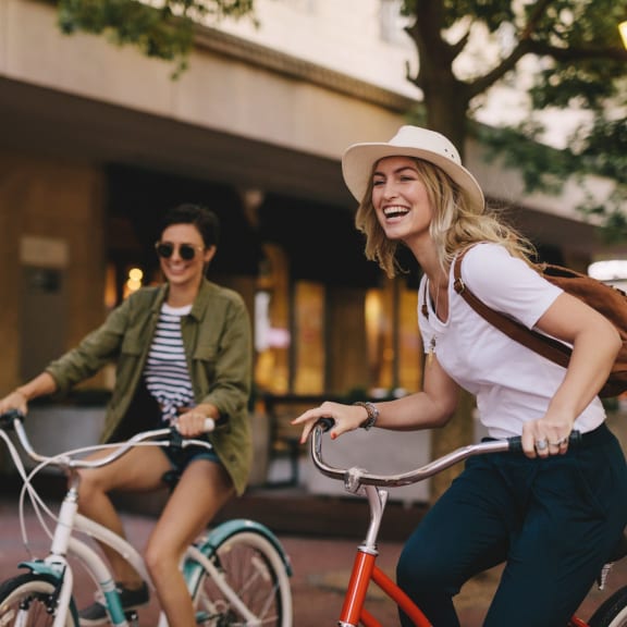 two women riding bicycles down the street on bikes