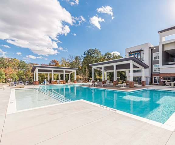 A large swimming pool in front of a building with a sunny sky above. at The Paramount Apartments, Atlanta, Georgia