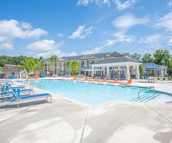 A large swimming pool with lounge chairs and a building in the background.