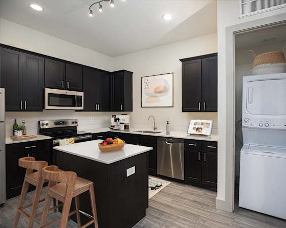 a kitchen with black cabinets and a white washer and dryer