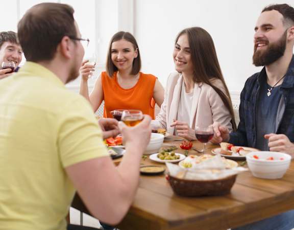 A group of people are gathered around a table enjoying a meal and drinks.