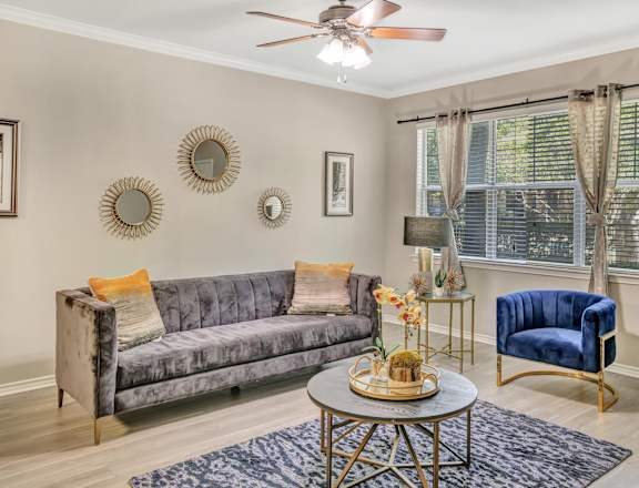 A living room with a grey couch, a blue chair, and a table with a vase of flowers on it.
