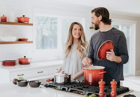 A man and woman are cooking together in a kitchen.