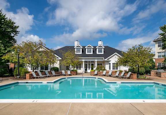 A large clubhouse with a pool in front.