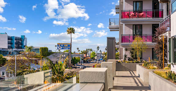 Modern building with a glass balcony overlooking a street at AMP 30 Apartments, San Diego, CA, 92116