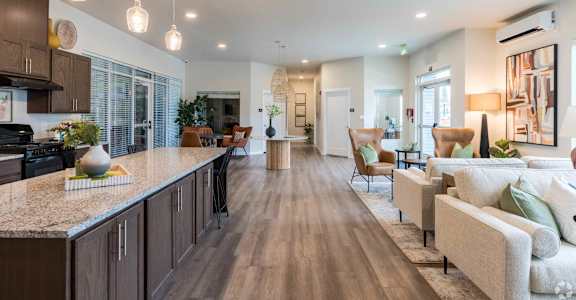 A modern kitchen with a long island and a living room with a couch.