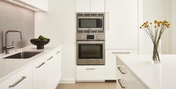 a white kitchen with stainless steel appliances and white cabinets