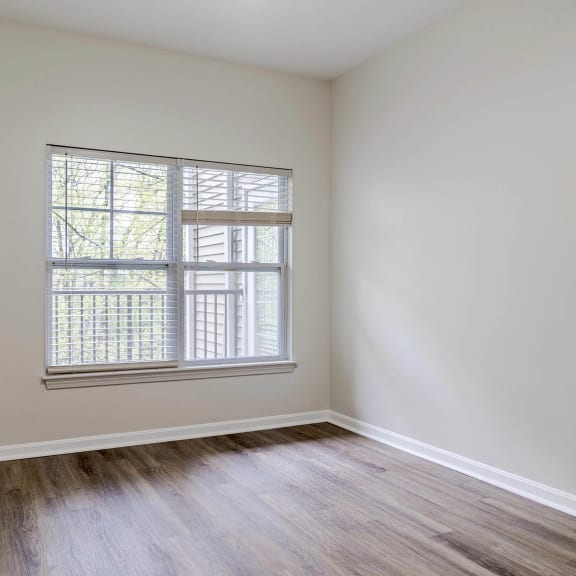 a bedroom with white walls and a window and wood floors