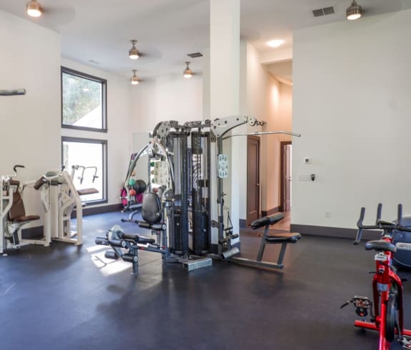 a fitness room with exercise equipment and windows