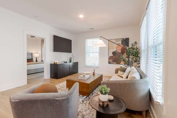 A modern open plan living and dining area with wooden floors and furniture at The Merchant Apartments, Charleston, SC