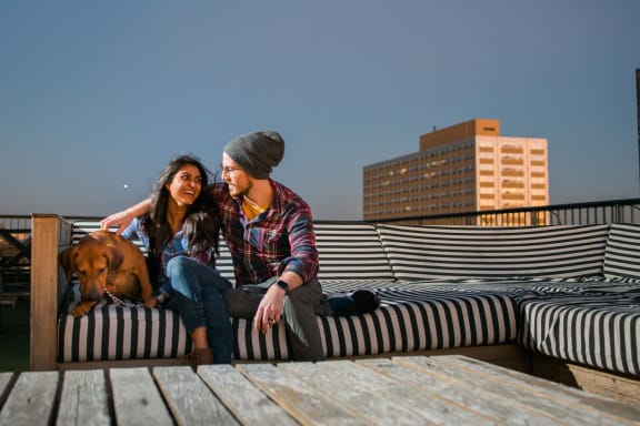 a man and woman sitting on a bench with a dog