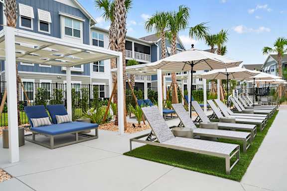 A row of lounge chairs are arranged on a patio.