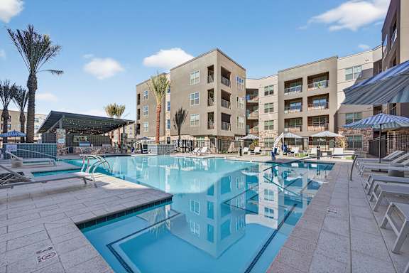 A large swimming pool in front of a building with a blue sky in the background.