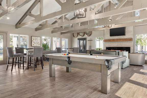 A pool table is in the middle of a room with a fireplace and a TV.