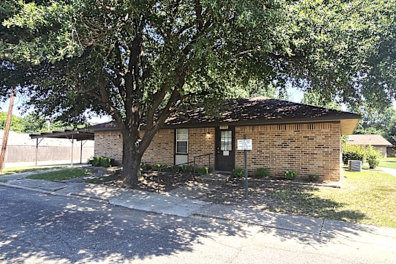 A small brick building with a black door and a sign on the front.