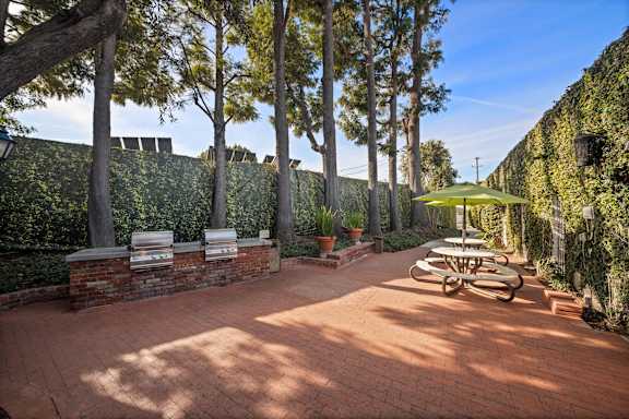 A patio with a table and chairs surrounded by a wall of green plants.