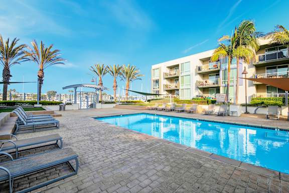 A swimming pool surrounded by palm trees and lounge chairs.