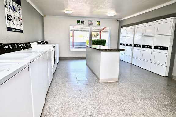 A laundromat with washers and dryers lined up.