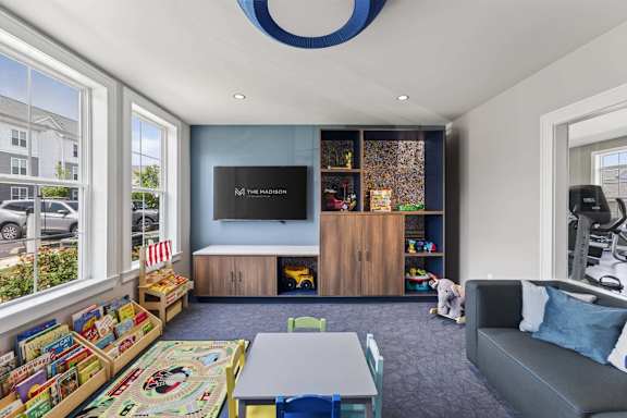 Indoor playroom with books, toys, child-size tables, and soft seating at The Madison at Marshfield.
