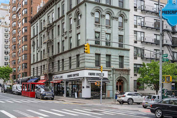 A street view of a city with cars, buildings, and a traffic light.