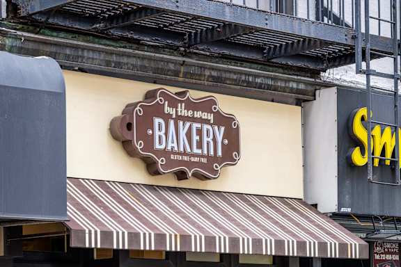 A bakery sign on a building with a striped awning.