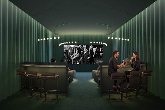 Two people are sitting at a bar with a green striped wall behind them.
