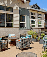 A patio with chairs and a table is in front of a building.