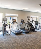 a gym with cardio equipment in a room with windows