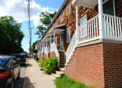 Thumbnail 2 of 2 - a brick building with white railings and a sidewalk