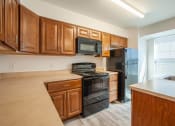 Thumbnail 3 of 6 - a kitchen with wooden cabinets and black appliances