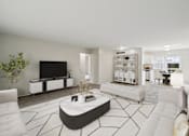 Thumbnail 5 of 5 - A modern living room with a white sofa, a black coffee table, and a flat-screen TV.