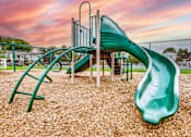 Thumbnail 1 of 5 - A playground with a green slide and a climbing frame.