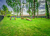Thumbnail 1 of 6 - A playground with a green lawn and a black fence.