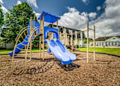 Thumbnail 4 of 6 - A playground with a blue slide and a wooden structure.
