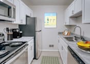 Thumbnail 2 of 5 - A kitchen with a black stove top oven and white cabinets.