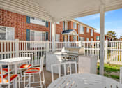 Thumbnail 6 of 8 - A patio with a grill and chairs is set up.