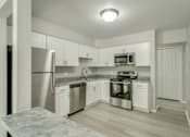 Thumbnail 5 of 6 - A kitchen with white cabinets and stainless steel appliances.