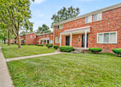Thumbnail 1 of 3 - A red brick building with a white awning and a green lawn in front.